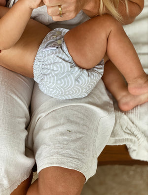 Baby being nursed by mother wearing a Little Eco Baby Modern Cloth Nappy in the print Sandshells.