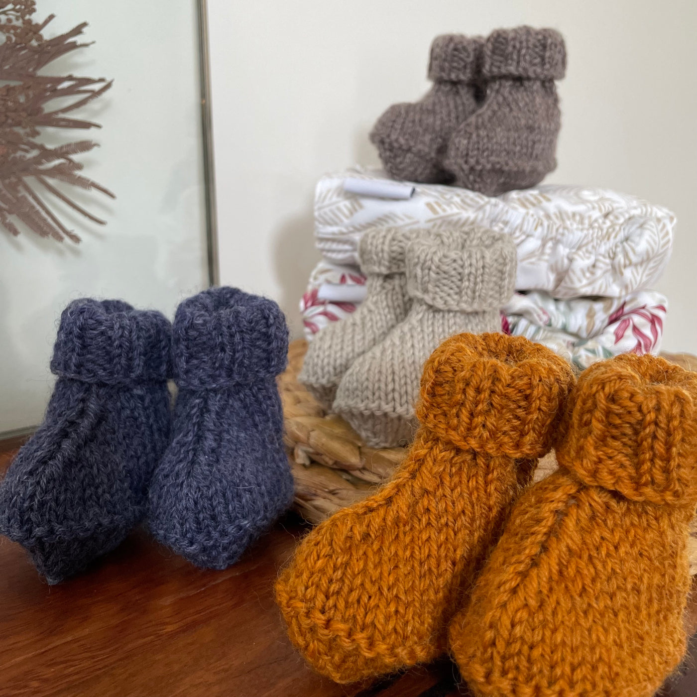 4 different styled baby booties on display with cloth nappies